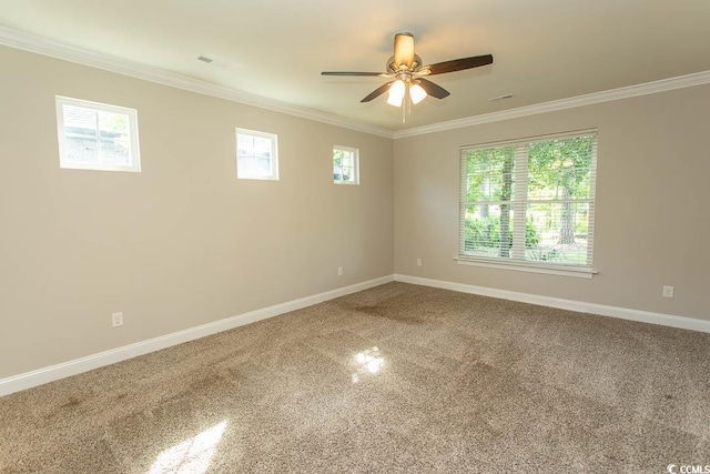 carpeted spare room with baseboards, ornamental molding, ceiling fan, and plenty of natural light