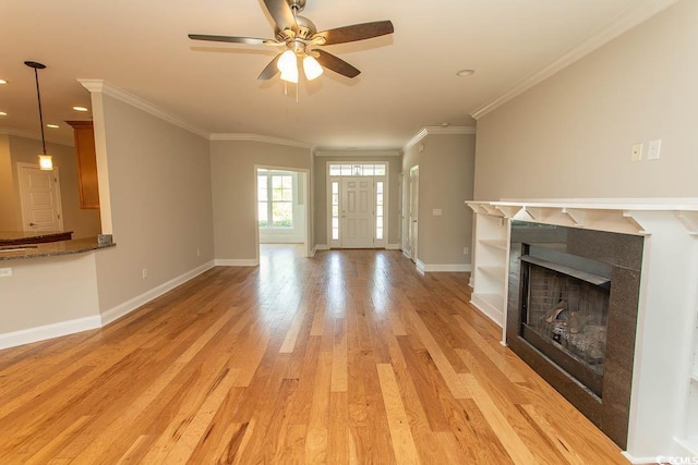 unfurnished living room with a ceiling fan, a fireplace, baseboards, light wood-style floors, and ornamental molding