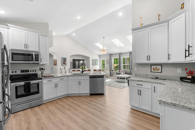 kitchen featuring white cabinetry, lofted ceiling with skylight, light wood-type flooring, and appliances with stainless steel finishes