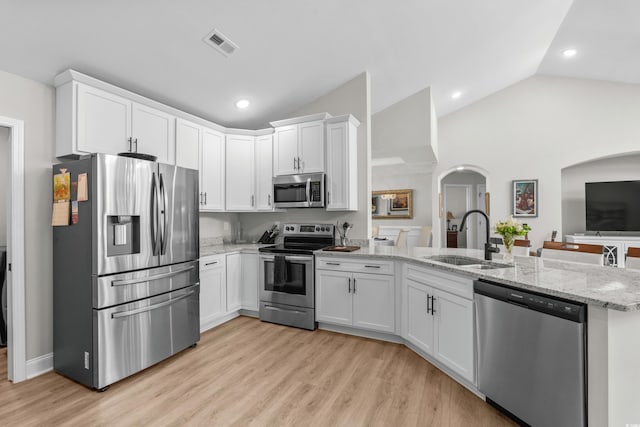 kitchen featuring visible vents, a sink, a peninsula, arched walkways, and appliances with stainless steel finishes
