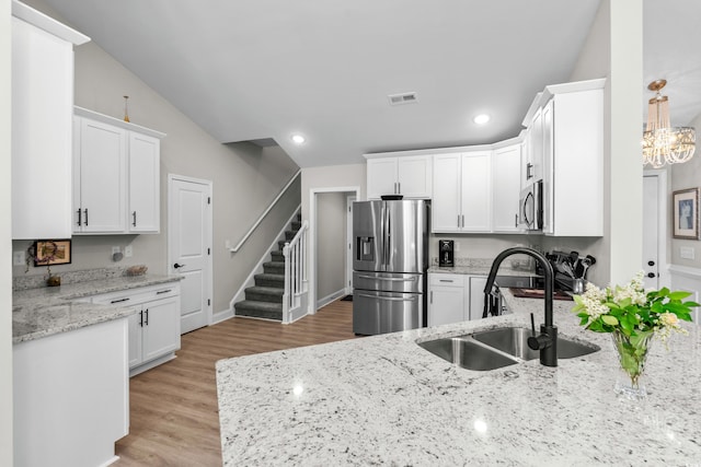 kitchen with a sink, stainless steel appliances, white cabinets, light stone counters, and recessed lighting