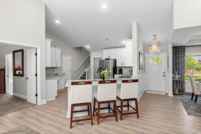 kitchen with light wood-style flooring, a sink, freestanding refrigerator, a notable chandelier, and white cabinetry