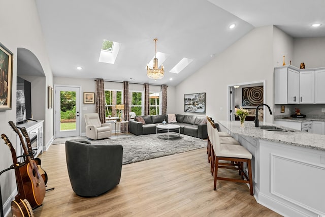 living room with light wood finished floors, a skylight, high vaulted ceiling, and recessed lighting