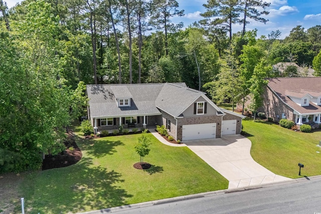 view of front of house with concrete driveway, a shingled roof, a porch, a front yard, and brick siding