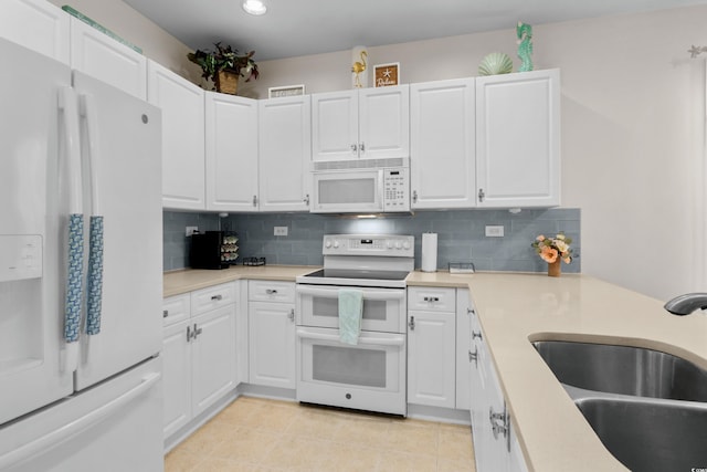 kitchen with white appliances, white cabinetry, decorative backsplash, and a sink