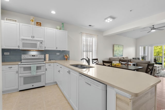 kitchen featuring decorative backsplash, a peninsula, white appliances, open floor plan, and a sink