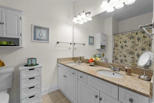 bathroom with double vanity, a sink, tile patterned floors, and toilet