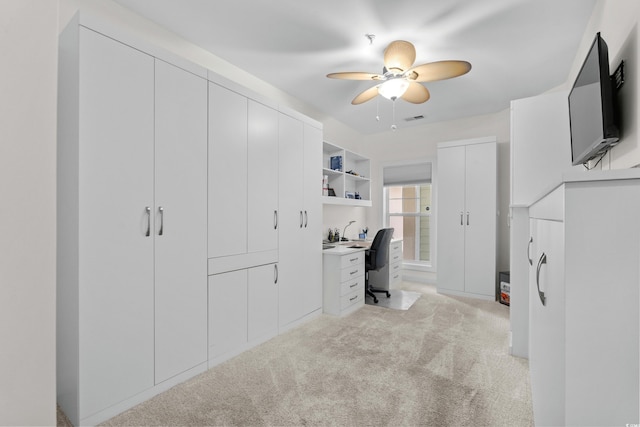 unfurnished office with light colored carpet, a ceiling fan, and visible vents
