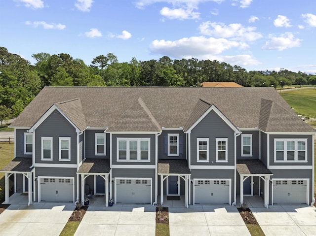 townhome / multi-family property featuring an attached garage, a shingled roof, and driveway