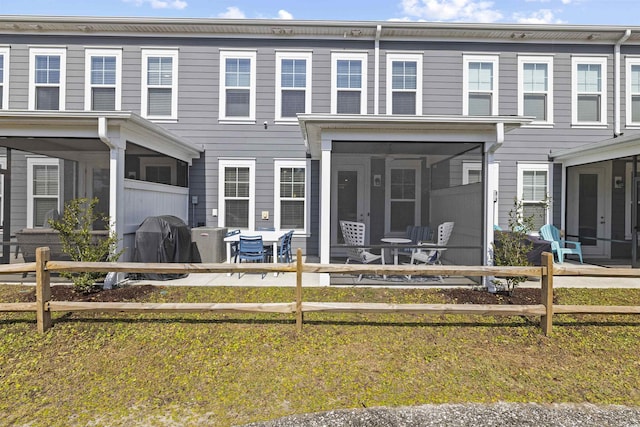 rear view of property with a sunroom, a patio area, and fence