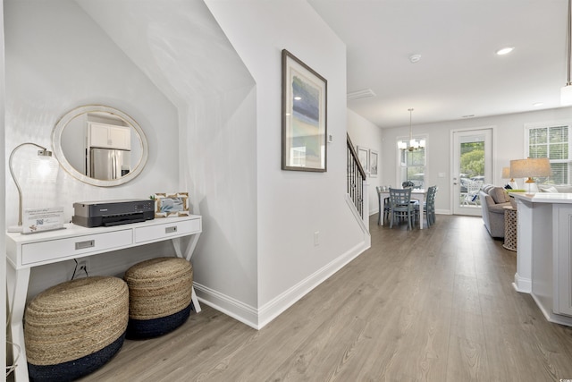 hallway featuring baseboards, recessed lighting, light wood-style flooring, and a notable chandelier