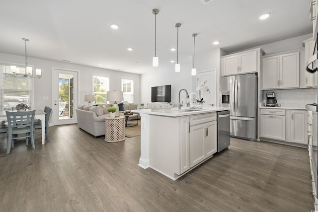 kitchen featuring light countertops, a sink, dark wood finished floors, appliances with stainless steel finishes, and backsplash