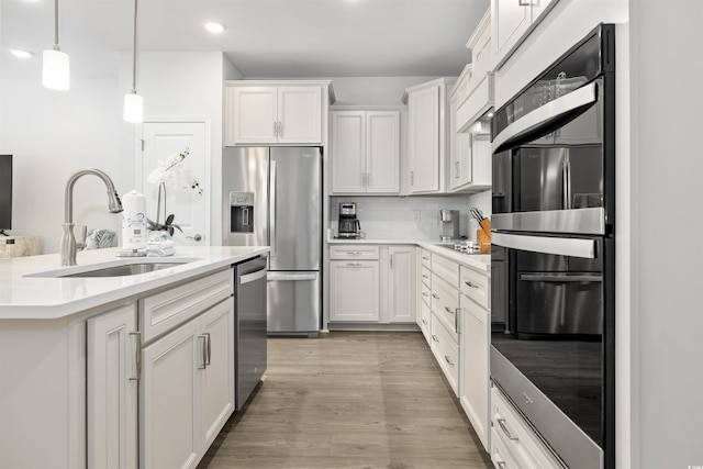 kitchen featuring tasteful backsplash, a sink, white cabinets, stainless steel appliances, and recessed lighting