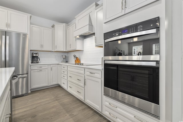 kitchen with light countertops, stainless steel appliances, light wood-style flooring, and tasteful backsplash
