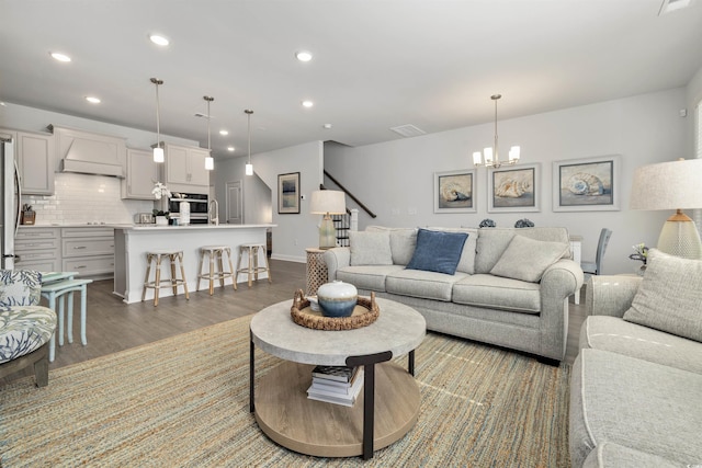 living area with visible vents, stairs, wood finished floors, recessed lighting, and a chandelier