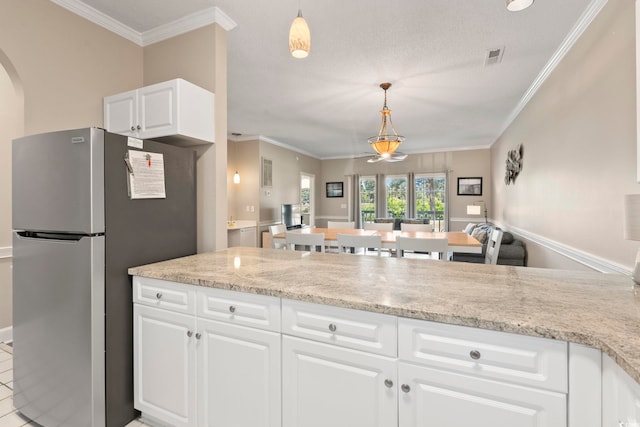 4771 Wild Iris Dr Unit 103, Myrtle Beach, SC 29577 - kitchen featuring crown molding, hanging light fixtures, freestanding refrigerator, and white cabinets