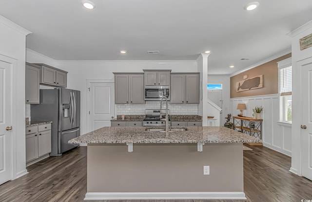 kitchen featuring gray cabinets, a kitchen island with sink, visible vents, appliances with stainless steel finishes, and light stone counters