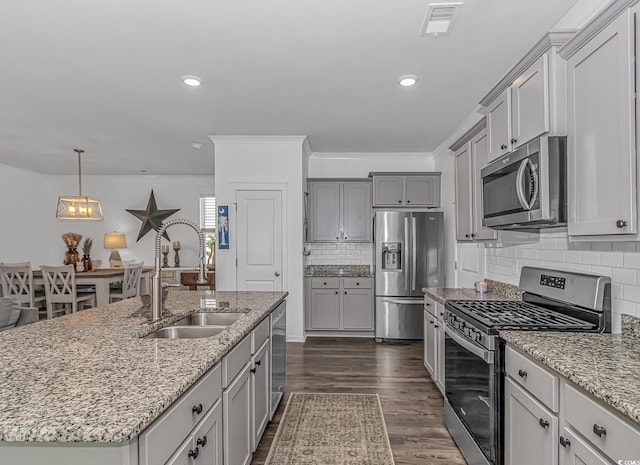 kitchen with a sink, gray cabinets, light stone countertops, and stainless steel appliances