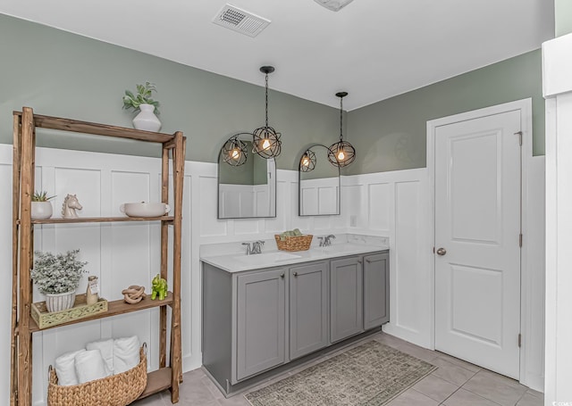 full bath featuring a sink, tile patterned floors, wainscoting, and a decorative wall