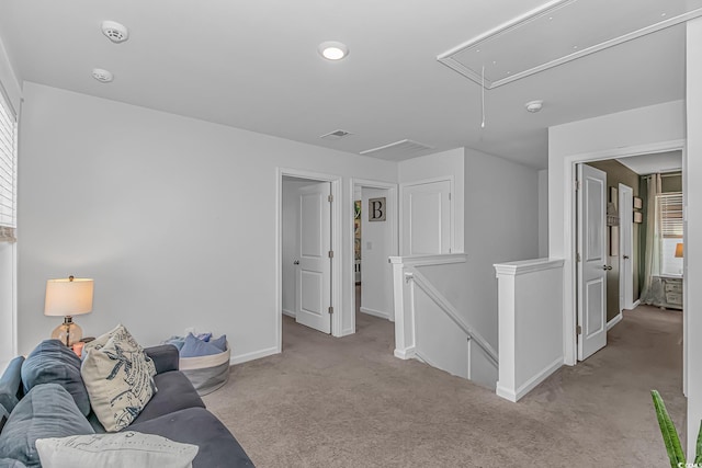 carpeted living area featuring baseboards and attic access
