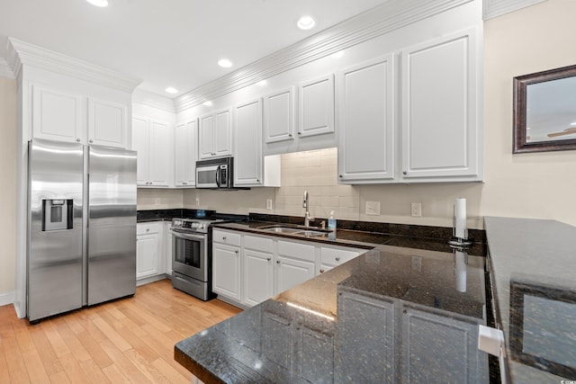 kitchen featuring a sink, appliances with stainless steel finishes, light wood-style flooring, and white cabinetry