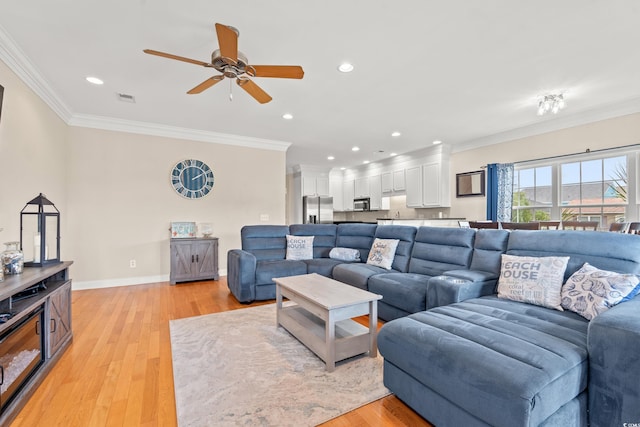 living area featuring visible vents, ornamental molding, and a ceiling fan