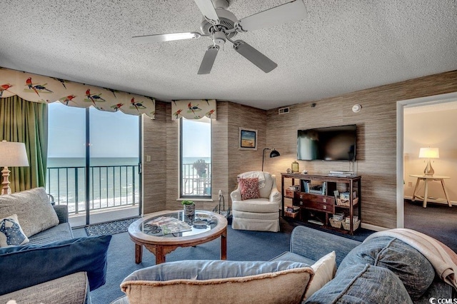carpeted living area with ceiling fan, a textured ceiling, and visible vents