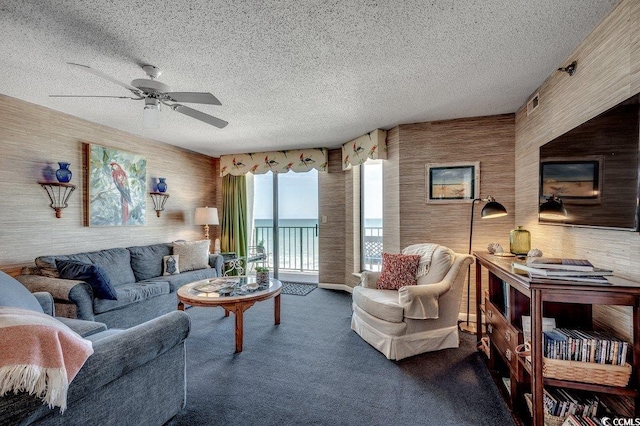 living room with ceiling fan, a textured ceiling, and dark colored carpet