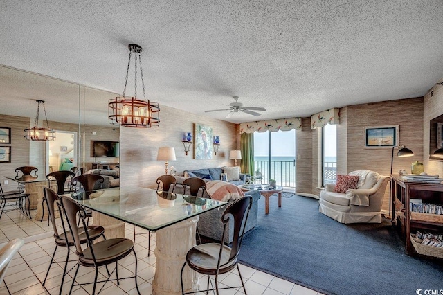 kitchen with ceiling fan with notable chandelier, a textured ceiling, light tile patterned flooring, open floor plan, and hanging light fixtures