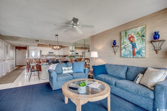 living room featuring light tile patterned floors, a textured ceiling, a ceiling fan, and visible vents