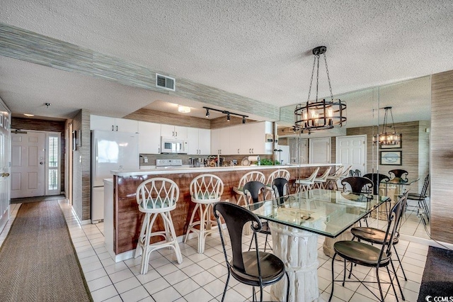 dining space featuring visible vents, an inviting chandelier, light tile patterned flooring, and a textured ceiling