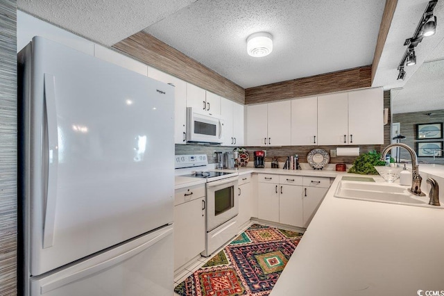 kitchen featuring a textured ceiling, white appliances, tasteful backsplash, and a sink