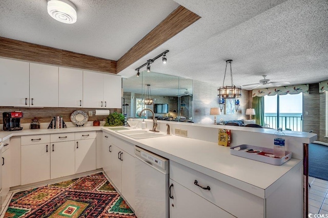kitchen featuring a peninsula, a sink, open floor plan, a textured ceiling, and dishwasher