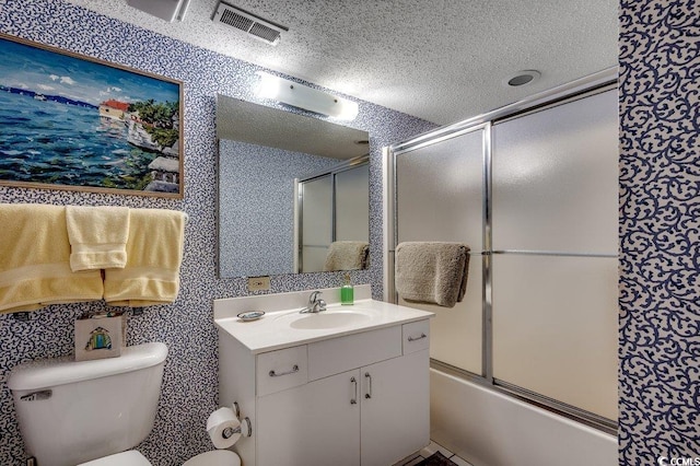 bathroom with a textured ceiling, toilet, bath / shower combo with glass door, visible vents, and vanity