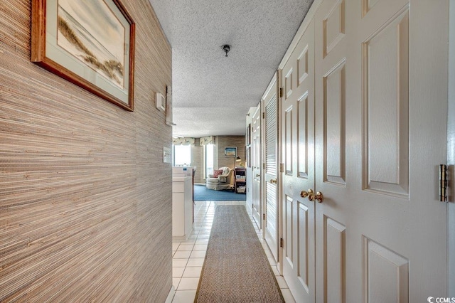 hallway featuring a textured ceiling and light tile patterned floors