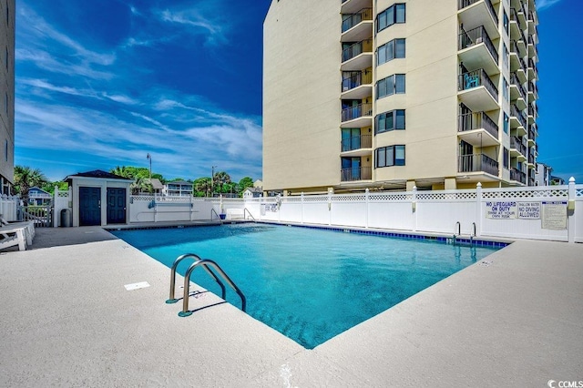 community pool with a patio and fence