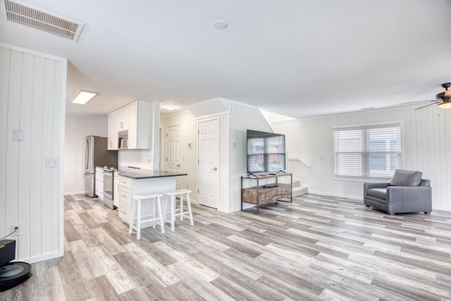 1023 S Sea Bridge Ct, Surfside Beach, SC 29575 - kitchen featuring light wood-type flooring, a breakfast bar area, appliances with stainless steel finishes, white cabinets, and a ceiling fan