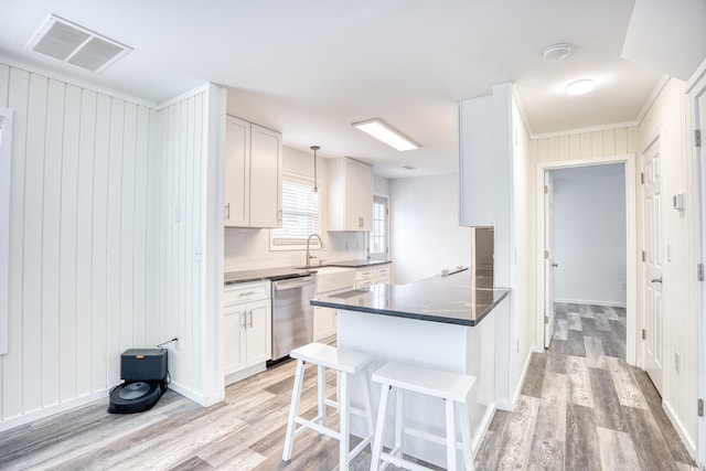 1023 S Sea Bridge Ct, Surfside Beach, SC 29575 - kitchen featuring dishwasher, light wood-type flooring, dark countertops, decorative backsplash, and a breakfast bar area