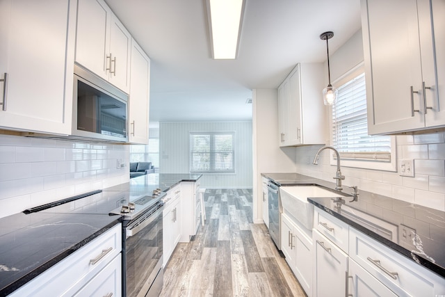 1023 S Sea Bridge Ct, Surfside Beach, SC 29575 - kitchen with stainless steel appliances, light wood-type flooring, a sink, white cabinetry, and dark stone counters