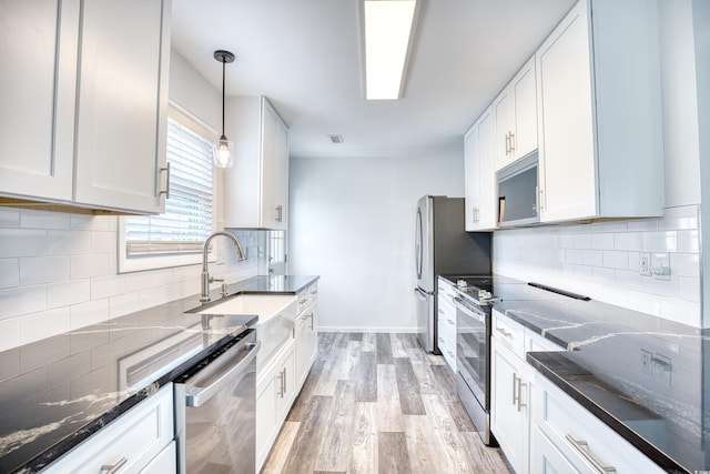1023 S Sea Bridge Ct, Surfside Beach, SC 29575 - kitchen with stainless steel appliances, a sink, light wood finished floors, backsplash, and dark stone countertops