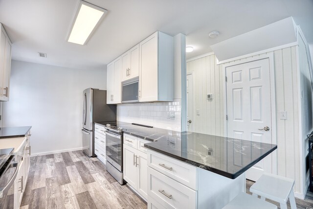 1023 S Sea Bridge Ct, Surfside Beach, SC 29575 - kitchen with appliances with stainless steel finishes, white cabinetry, decorative backsplash, a kitchen bar, and a peninsula