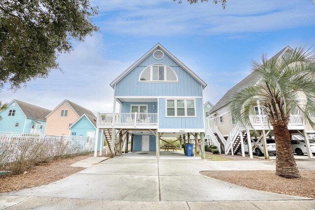 1023 S Sea Bridge Ct, Surfside Beach, SC 29575 - coastal inspired home with stairs, covered porch, a carport, and driveway