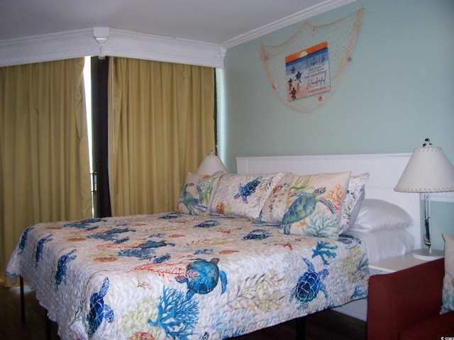 bedroom with ornamental molding and wood finished floors