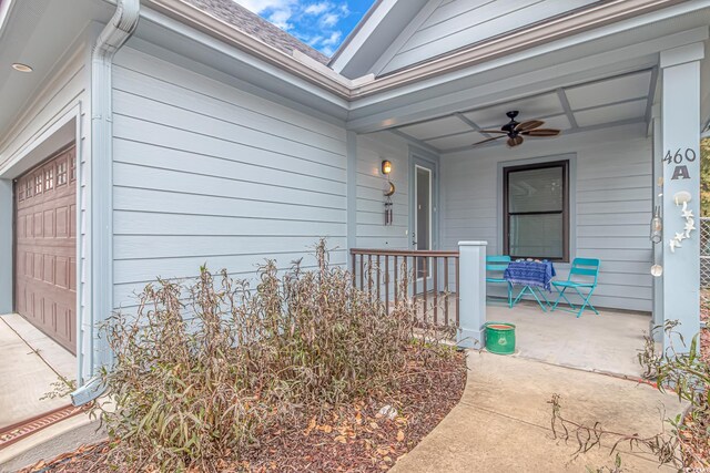 doorway to property with a porch, ceiling fan, and a shingled roof