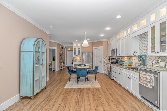 kitchen featuring stainless steel appliances, baseboards, a sink, decorative backsplash, and crown molding