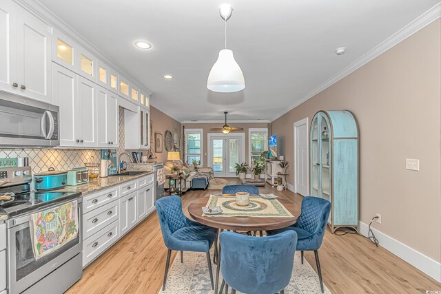 kitchen featuring stainless steel appliances, light wood-type flooring, baseboards, white cabinets, and tasteful backsplash