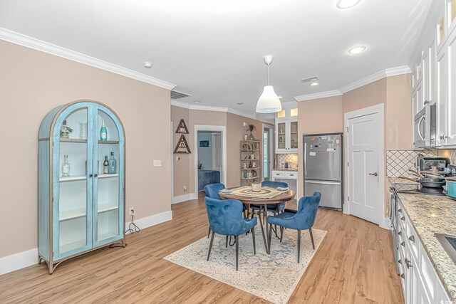 dining room featuring light wood-type flooring, crown molding, baseboards, and recessed lighting