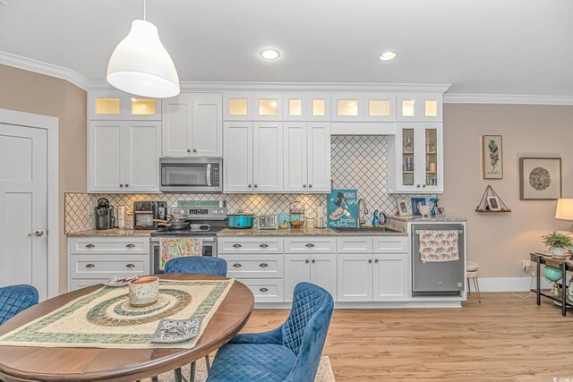 kitchen with stainless steel appliances, ornamental molding, a sink, tasteful backsplash, and light wood-style flooring