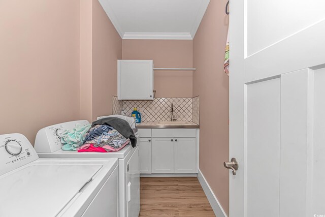 washroom with washer and dryer, cabinet space, crown molding, and light wood-style flooring