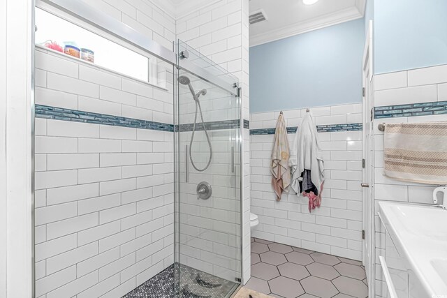 bathroom featuring ornamental molding, tile walls, a stall shower, tile patterned floors, and wainscoting